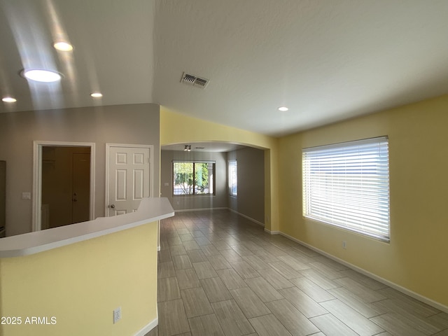 10817 W Wilshire Dr, Avondale, AZ 85392 - empty room with visible vents, baseboards, wood finish floors, arched walkways, and vaulted ceiling