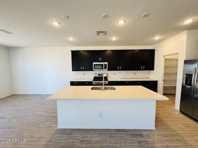 47267 W Mellen Ln, Maricopa, AZ 85139 - kitchen featuring appliances with stainless steel finishes, dark cabinets, light wood-style floors, light countertops, and recessed lighting