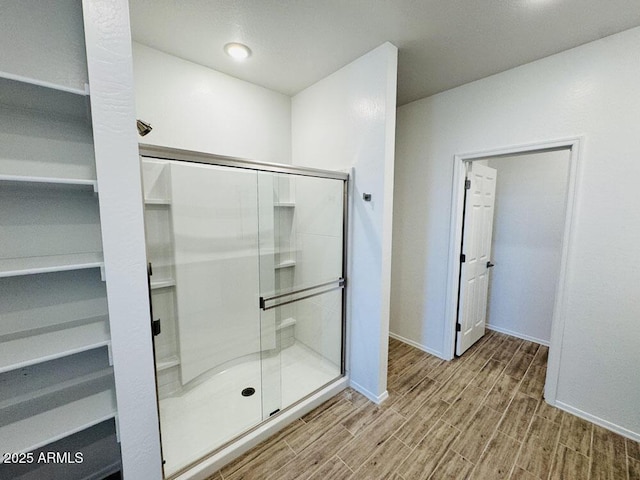 47267 W Mellen Ln, Maricopa, AZ 85139 - bathroom featuring wood finished floors, a shower stall, a walk in closet, and baseboards
