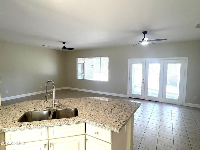 kitchen with light stone counters, white cabinets, light tile patterned floors, ceiling fan, and sink