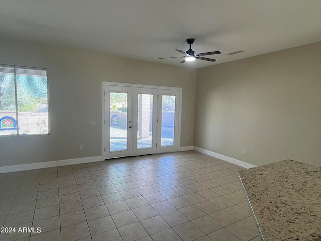 empty room with ceiling fan, french doors, plenty of natural light, and light tile patterned floors