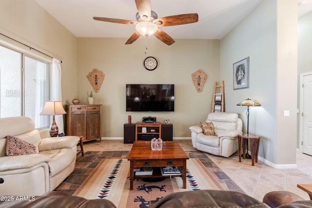 living room with stone tile floors, a ceiling fan, and baseboards