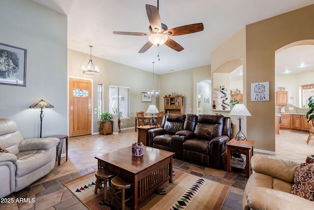 living room featuring arched walkways and ceiling fan with notable chandelier