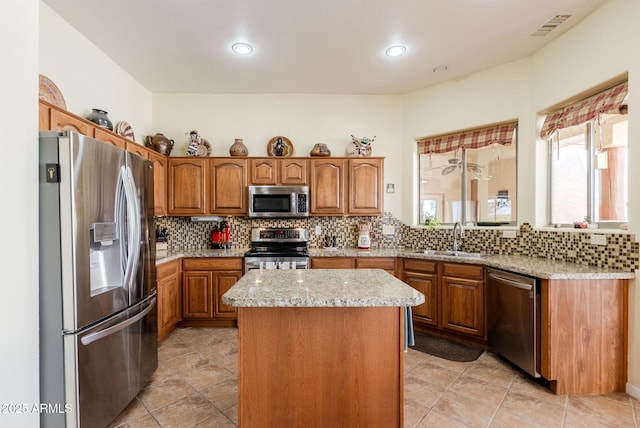 kitchen with visible vents, decorative backsplash, a kitchen island, a sink, and appliances with stainless steel finishes