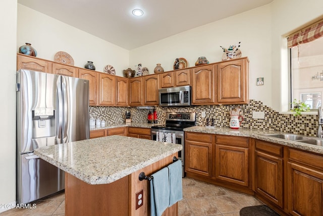 kitchen featuring a kitchen island, brown cabinets, a sink, backsplash, and stainless steel appliances