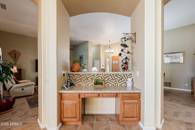 interior space with decorative backsplash, visible vents, vanity, baseboards, and an inviting chandelier