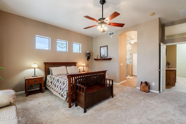 carpeted bedroom featuring arched walkways, baseboards, visible vents, and ensuite bathroom