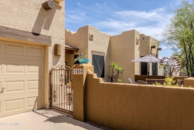 view of front of house with fence, a gate, stucco siding, and stone siding