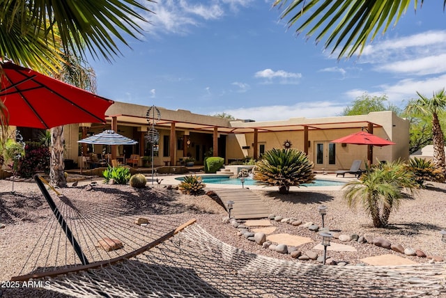 back of house featuring a patio, an outdoor pool, stucco siding, and french doors