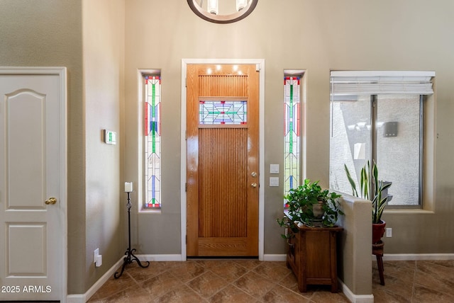 foyer featuring baseboards, plenty of natural light, and a high ceiling