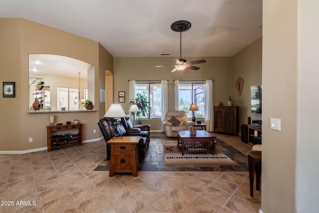 living room with arched walkways, baseboards, and a ceiling fan