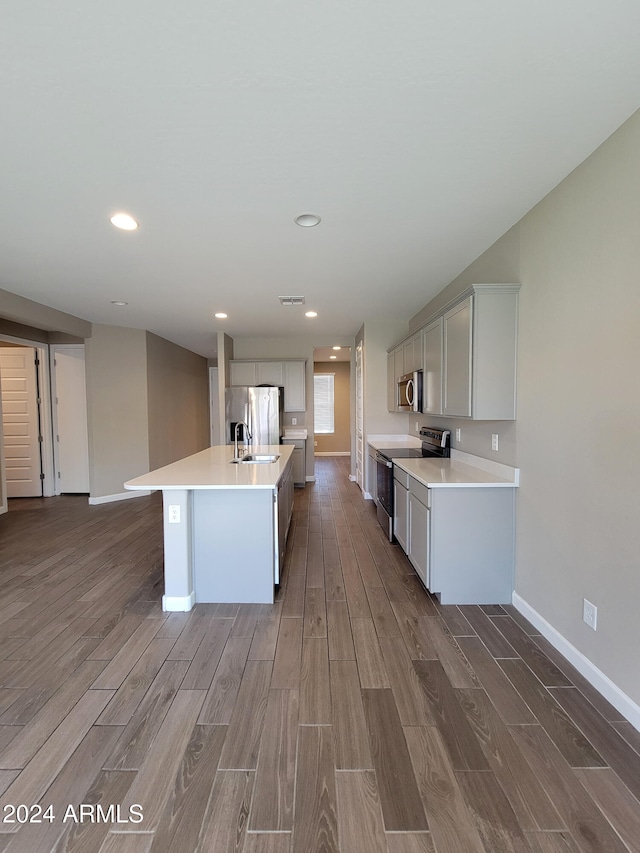 kitchen featuring sink, a center island with sink, dark hardwood / wood-style floors, and appliances with stainless steel finishes