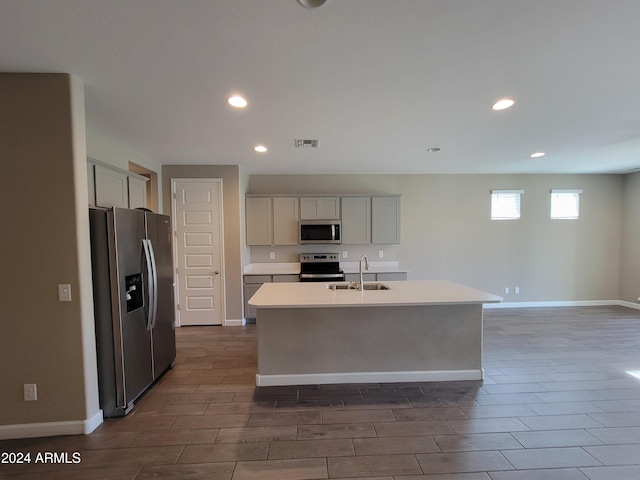 kitchen featuring dark hardwood / wood-style floors, sink, stainless steel appliances, and an island with sink