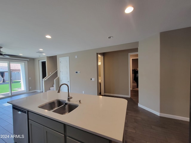 kitchen featuring gray cabinetry, dishwasher, sink, dark hardwood / wood-style floors, and a center island with sink