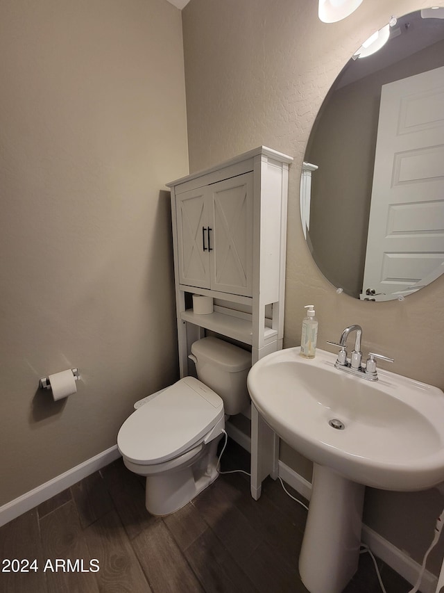 bathroom with toilet, wood-type flooring, and sink