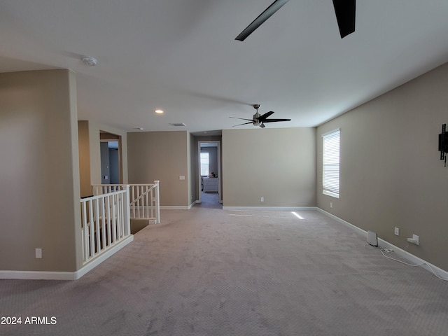 unfurnished room featuring ceiling fan, a healthy amount of sunlight, and light carpet