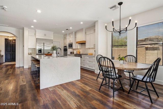 9904 E S Bend Dr, Scottsdale, AZ 85255 - kitchen with built in appliances, a chandelier, a sink, dark wood finished floors, and arched walkways