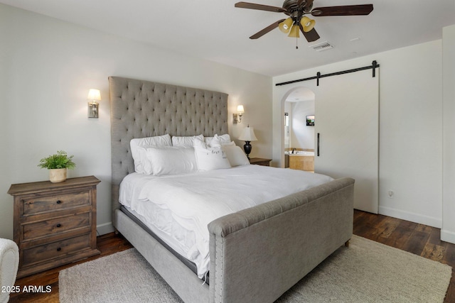 9904 E S Bend Dr, Scottsdale, AZ 85255 - bedroom featuring a barn door, wood finished floors, arched walkways, baseboards, and connected bathroom