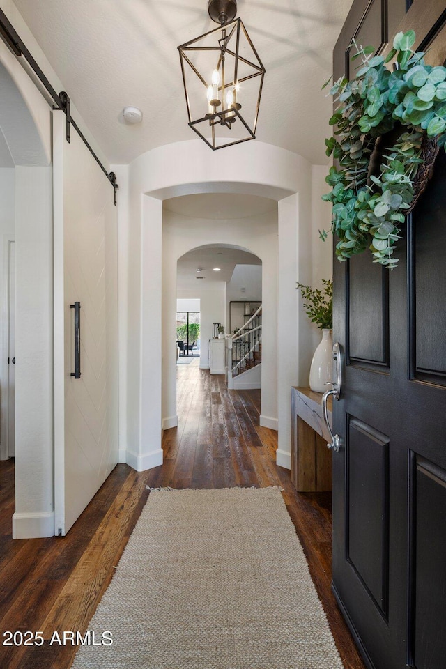 9904 E S Bend Dr, Scottsdale, AZ 85255 - entrance foyer featuring a barn door, arched walkways, dark wood-type flooring, and baseboards