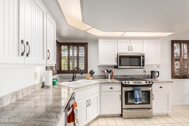 kitchen with appliances with stainless steel finishes, sink, white cabinets, light tile patterned floors, and light stone counters