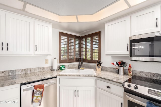 kitchen featuring stainless steel appliances, sink, white cabinets, and light stone counters