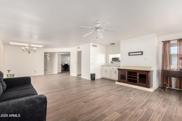 living room with hardwood / wood-style flooring and ceiling fan with notable chandelier