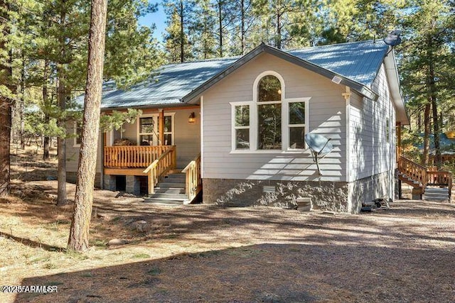 view of side of property with metal roof, covered porch, and stairway