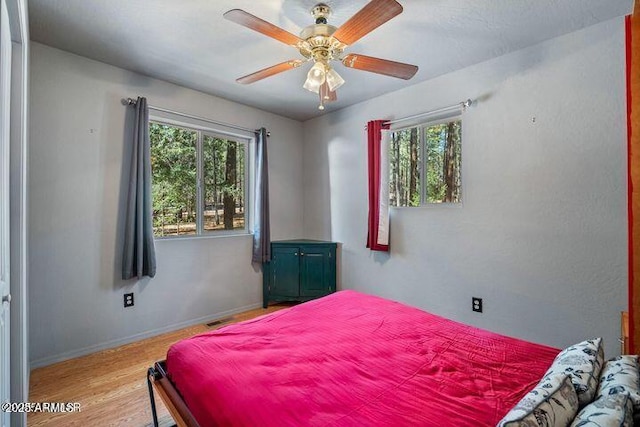 bedroom featuring ceiling fan, baseboards, and wood finished floors