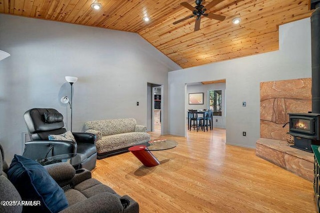 living room featuring high vaulted ceiling, wood finished floors, wooden ceiling, ceiling fan, and a wood stove