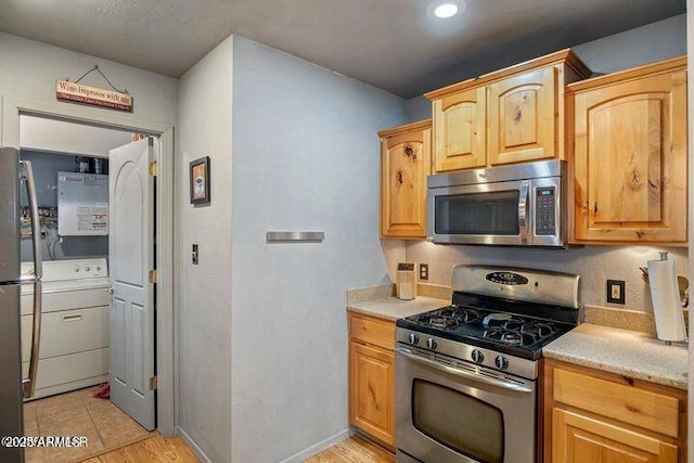 kitchen featuring washer / clothes dryer, baseboards, appliances with stainless steel finishes, and light brown cabinetry