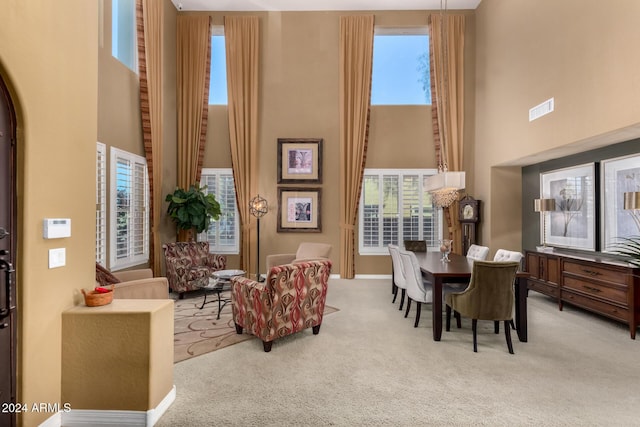 sitting room featuring light carpet, a high ceiling, and a healthy amount of sunlight