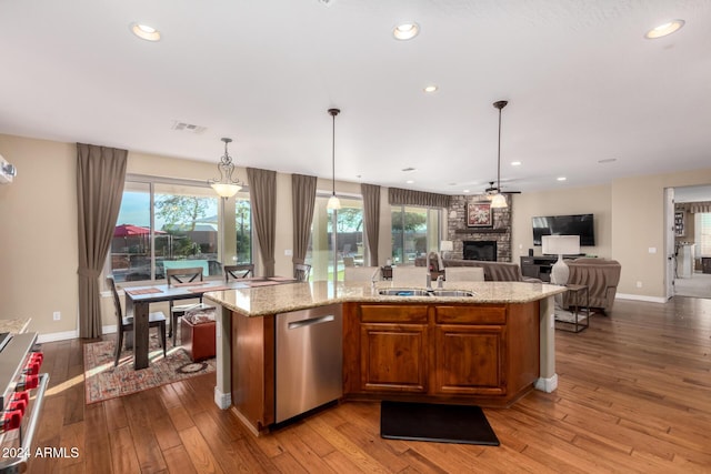 kitchen with a center island with sink, stainless steel appliances, a wealth of natural light, and light hardwood / wood-style flooring