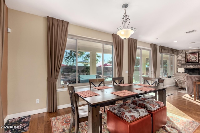 dining room featuring hardwood / wood-style flooring and a stone fireplace