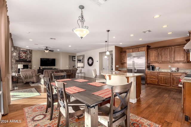 dining space with dark hardwood / wood-style floors, a fireplace, sink, and ceiling fan