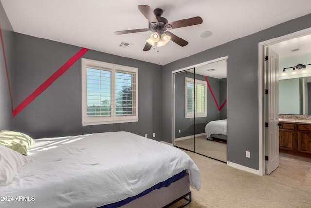 bedroom with connected bathroom, light colored carpet, a closet, and ceiling fan