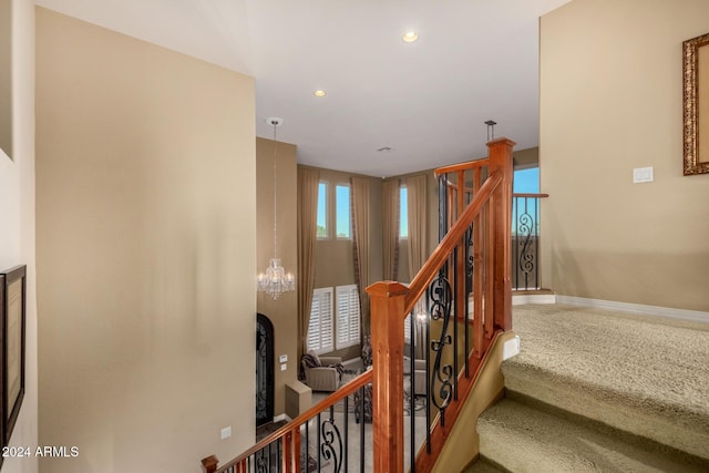 staircase featuring carpet flooring and a notable chandelier