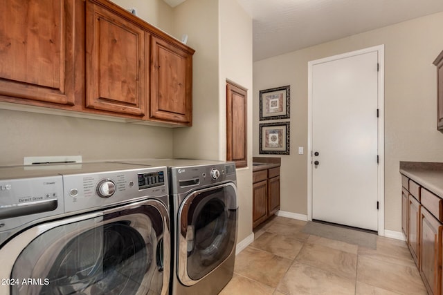 clothes washing area featuring washer and clothes dryer, light tile patterned flooring, and cabinets