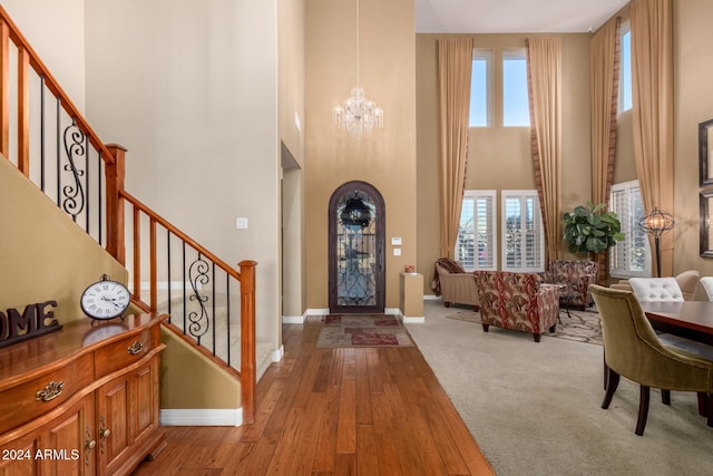 foyer entrance with wood-type flooring, a towering ceiling, and a healthy amount of sunlight