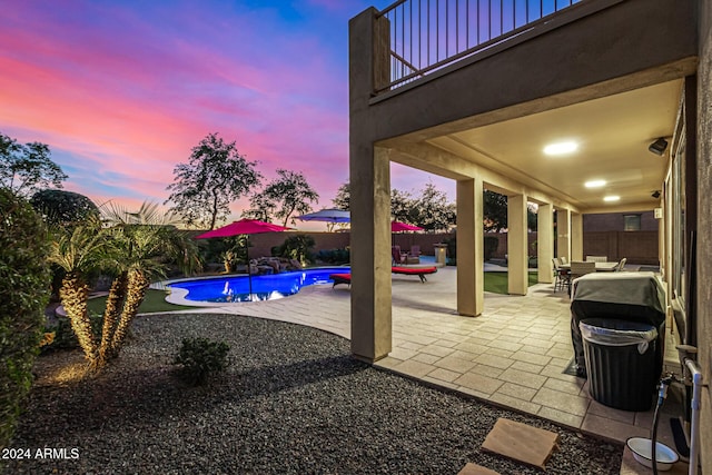 pool at dusk with a patio area