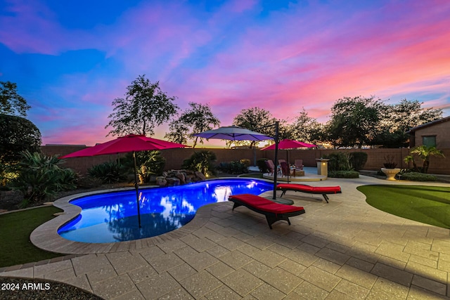 pool at dusk featuring a patio