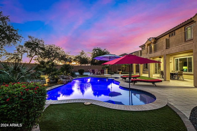 pool at dusk with a patio area