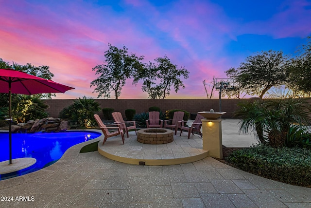 pool at dusk featuring a patio area and an outdoor fire pit