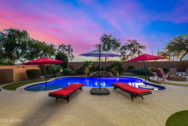 pool at dusk featuring a fire pit and a patio area