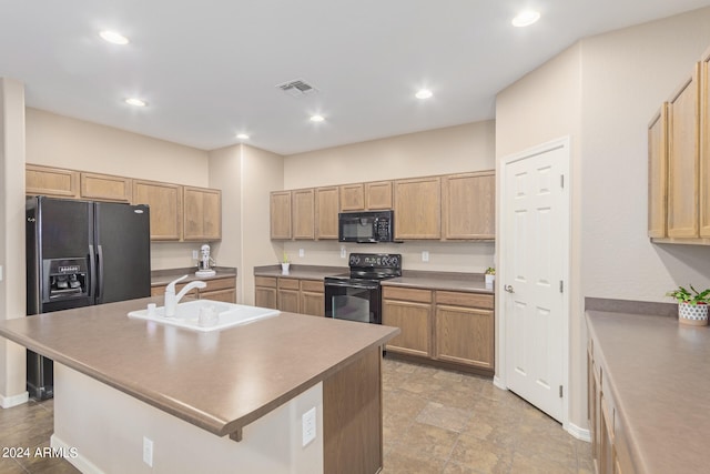 kitchen with an island with sink, light brown cabinets, black appliances, and sink