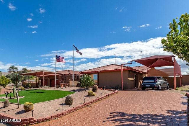 exterior space featuring a front yard, decorative driveway, a tile roof, and stucco siding