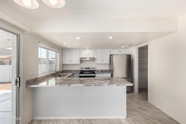 kitchen featuring appliances with stainless steel finishes, sink, white cabinets, kitchen peninsula, and light stone countertops