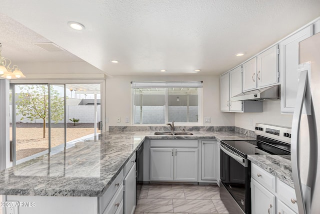 kitchen featuring appliances with stainless steel finishes, decorative light fixtures, sink, a notable chandelier, and a textured ceiling