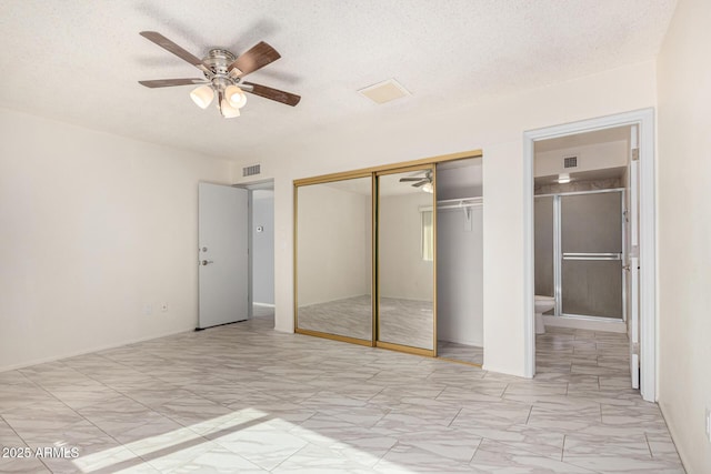 unfurnished bedroom featuring ceiling fan, connected bathroom, a closet, and a textured ceiling