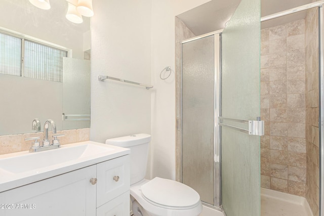 bathroom featuring vanity, a shower with door, and toilet