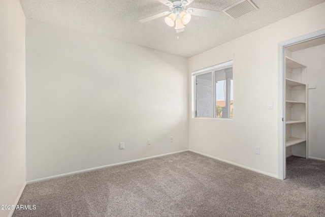 carpeted empty room featuring ceiling fan and a textured ceiling